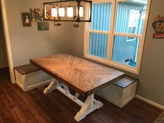 a wooden table sitting under a window next to a white bench on top of a hard wood floor