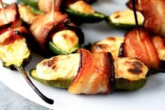 bacon wrapped jalapenos on a plate with toothpicks stuck in them