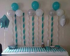 balloons and streamers are hanging from the wall above a table with a checkered tablecloth