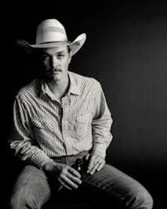 a man in a cowboy hat sitting on a stool