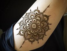 a woman's arm with a henna tattoo on the back of her shoulder