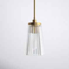 a brass and clear glass pendant light hanging from a ceiling fixture on a white wall