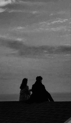 two people sitting on top of a roof looking at the sky