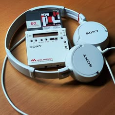 two sony headphones sitting on top of a wooden table next to a cd player