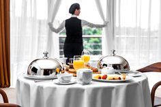 a woman standing in front of a table with food and drinks on top of it