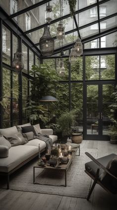 a living room filled with lots of furniture and plants inside of glass walls covered in hanging lights