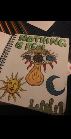 a notebook with an eye, sun and moon drawn on the cover that says nothing is real