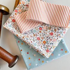 four folded fabric pieces sitting on top of each other next to a wooden mallet