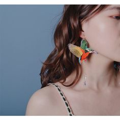 a woman wearing earrings with colorful birds on them