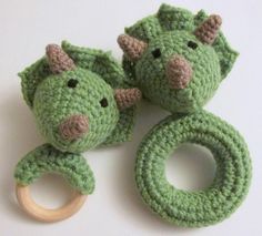 two green crocheted toys with wooden teeth and rings on a white table top