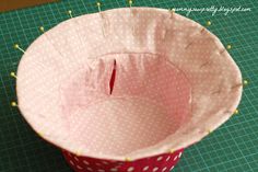 a pink polka dot paper cup sitting on top of a green cutting mat with pins