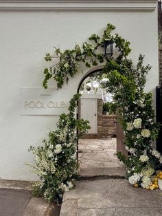 the entrance to pool club is decorated with white flowers and greenery