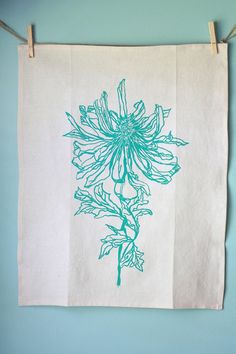 a tea towel hanging on a clothes line with blue flowers printed on the front and back