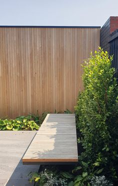 a wooden bench sitting in the middle of a garden next to a tall planter