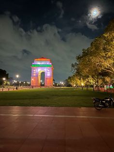 a motorcycle parked in front of a monument at night