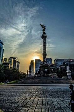 the sun is setting in front of a statue with an eagle on it's head