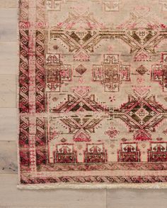 an old rug with red and beige colors on the floor in front of a wooden wall