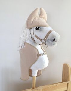 a white horse head mounted to the side of a wooden fence with a hat on it's head