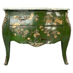 a green and gold painted dresser with flowers on the front, two drawers at the bottom