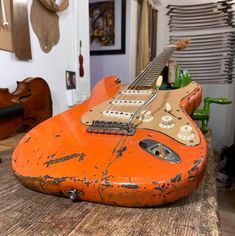 an orange guitar sitting on top of a wooden table