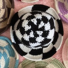 a crocheted black and white bowl on top of a pink blanket with circles around it