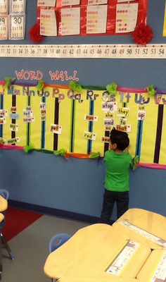 a young boy standing in front of a bulletin board with words written on the wall