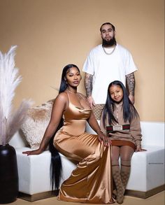 a man and two women sitting on a couch in front of a feathered pillow