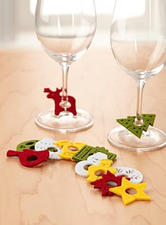 two wine glasses sitting next to each other on top of a wooden table with christmas decorations