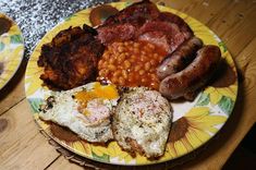 a plate with eggs, sausages, beans and other food on it sitting on a table