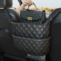 a woman holding a black purse in the back seat of a car with her hand on it