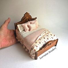 a hand is holding up a miniature bed