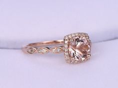 an engagement ring with a cushion cut morganite and diamond halos on the band