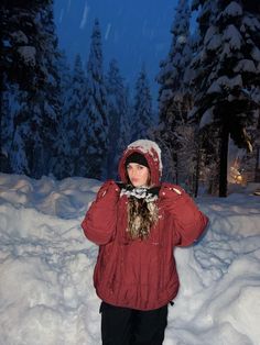 a woman standing in the snow wearing a red jacket