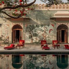 an outdoor pool with red chairs and paintings on the wall next to it's reflection