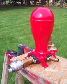 a red fire hydrant sitting on top of a piece of wood in the grass