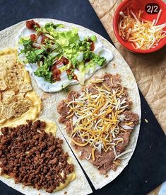 a tortilla topped with meat, cheese and other toppings next to a bowl of salad