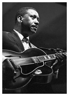 a black and white photo of a man playing an acoustic guitar