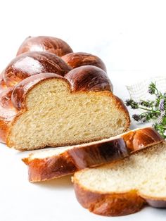 a loaf of bread sitting on top of a white counter next to sliced pieces of bread