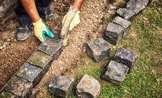 a man in yellow gloves is placing bricks into the ground