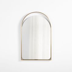 an oval mirror hanging on the wall with a gold frame and white walls behind it