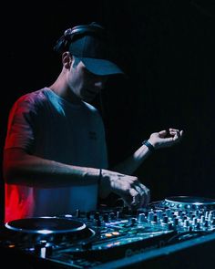 a dj mixing music in the dark with headphones on his ears and one hand