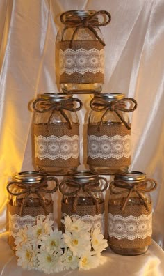 there are many mason jars with lace and flowers on the top one is filled with white daisies