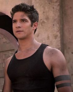 a man in black tank top standing next to a wall with his arm wrapped around him