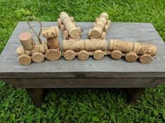 a small wooden train sitting on top of a table next to some logs and grass