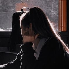 a woman sitting at a desk in front of a window talking on her cell phone