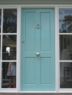 a person standing in front of a blue door with glass panes on the windows