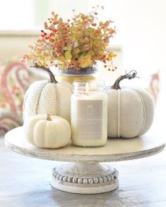 pumpkins and candles sit on a cake stand