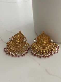 Antique gold-plated Ganesha temple earrings with intricate designs, featuring pearl and red ruby beads or pearl and emerald green beads. Perfect for South Indian weddings and bridal jewelry. Explore our heritage collection today. Earrings are Approximately 1.8 Inches Long and Approximately 1.4 Inches Wide   A Earring Weight is 0.5 oz  All our products are crafted using traditional skills from our rich heritage. The manual nature of these crafts means that irregularities or variations may inherent in the handcrafting process. Ganesha Temple, Temple Earrings, Jewelry Indian Wedding, Temple Jewelry, South Indian Weddings, South Indian Jewelry, Ruby Beads, Indian Wedding Jewelry, Green Beads