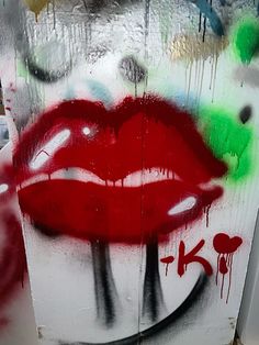 graffiti on the side of a building with a red lip painted on it's face