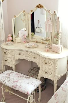 an antique white dressing table with mirror and stool